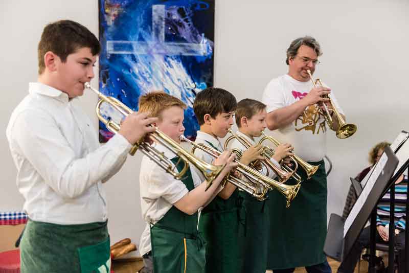 Trompete spielende Kinder mit ihrem Musiklehrer