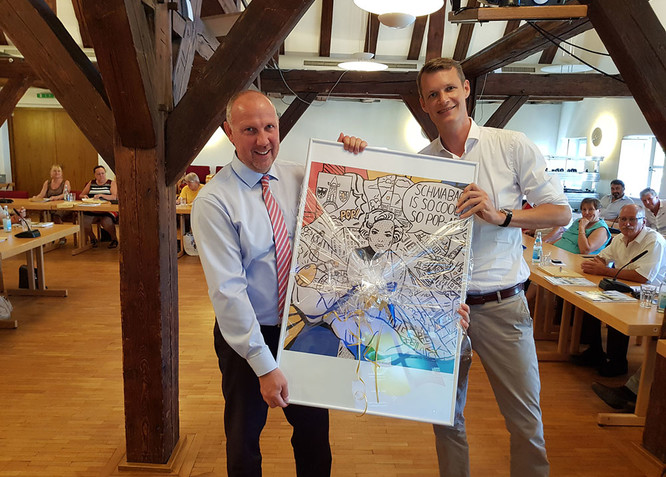 Frank Klingenberg (links) erhält von OB Matthias Thürauf zum Abschied nach der Stadtratssitzung ein Werk aus dem Wettbewerb „Schwabach Pop“, den Klingenberg ins Leben gerufen hatte.