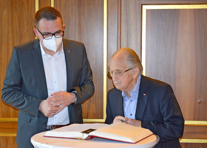 Oberbürgermeister Peter Reiß betrachtet zusammen mit Abba Naor den Eintrag in das Gästebuch.