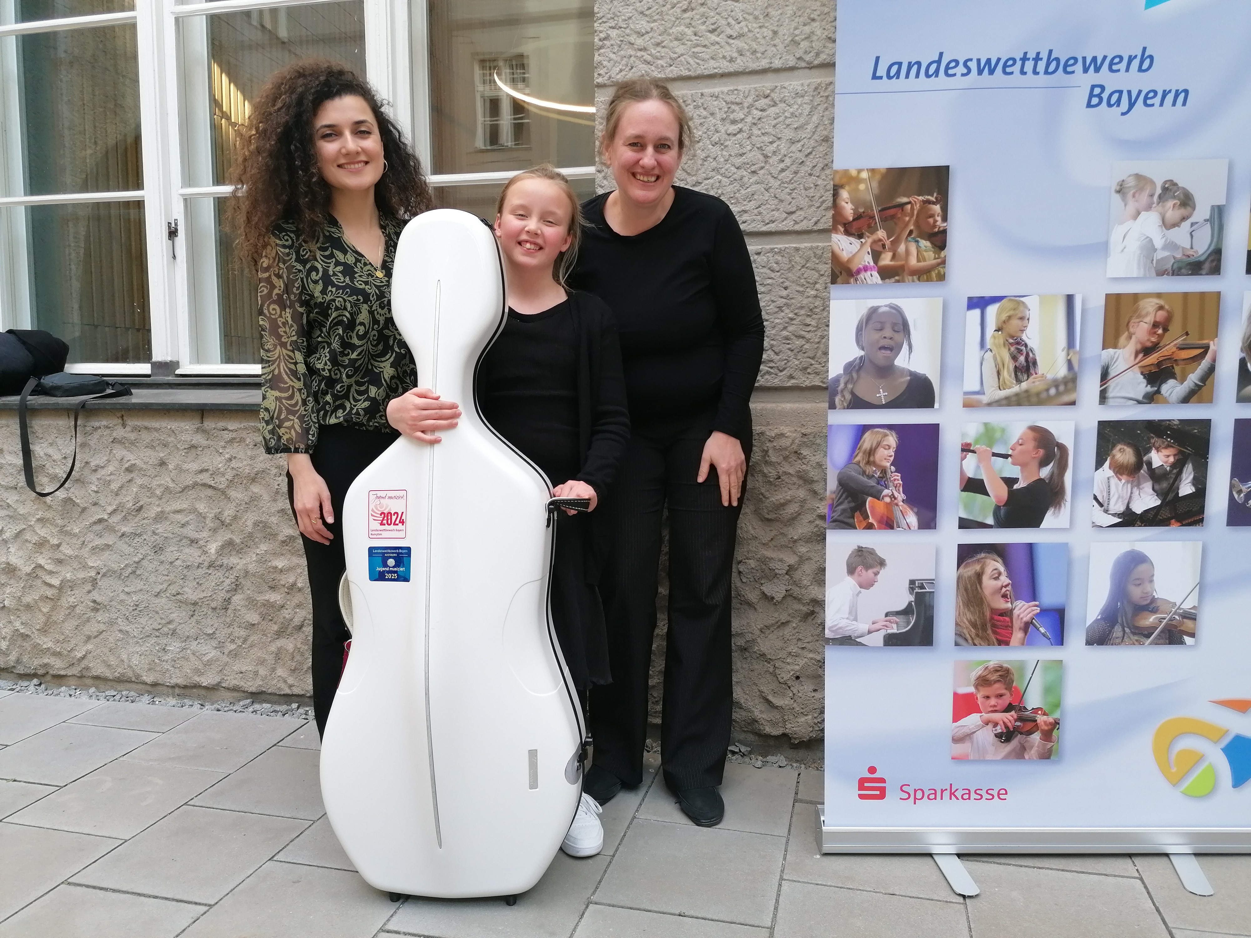 Schülerin mit Cello und zwei Lehrerinnen
