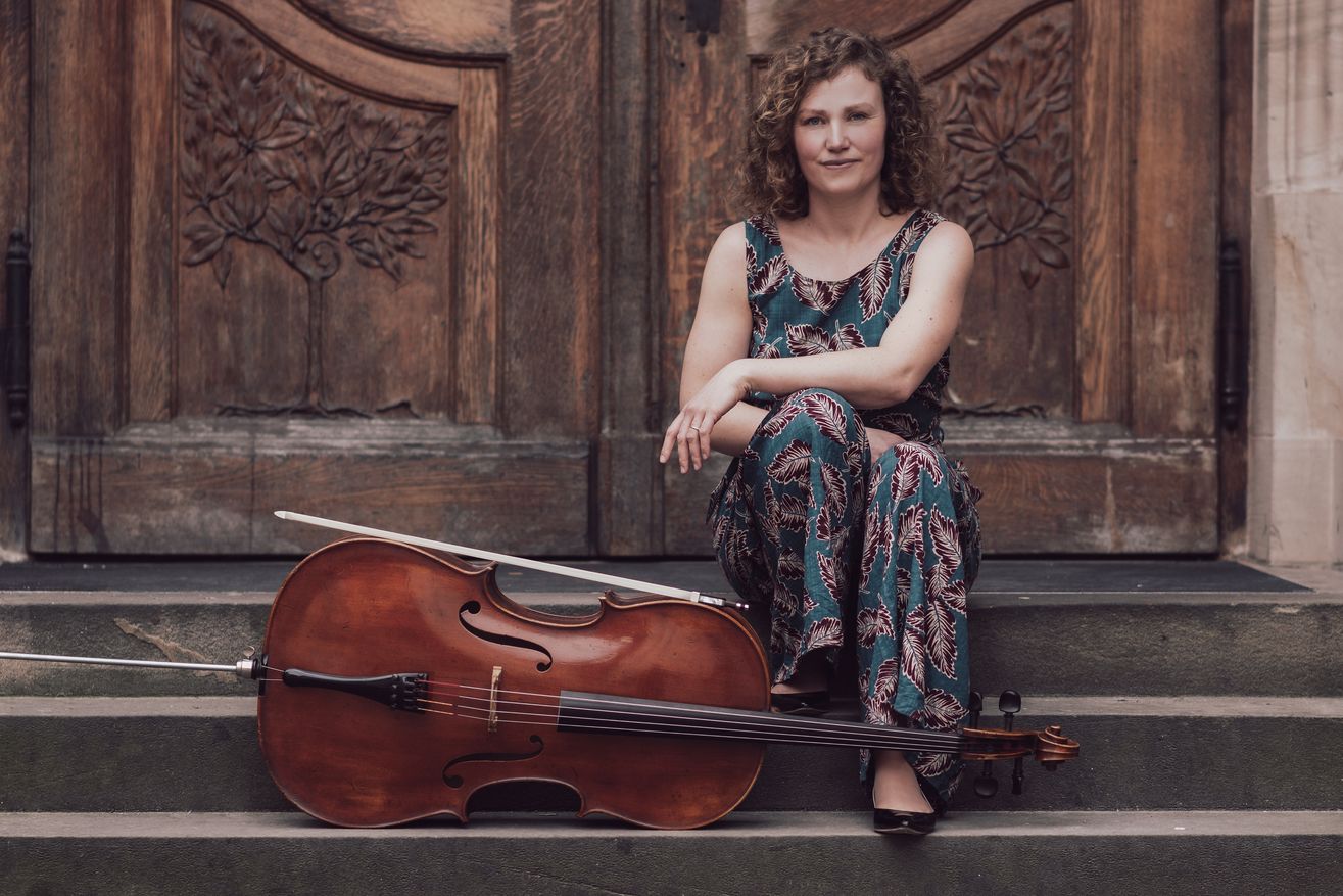 Frau sitzt mit Cello auf Treppe