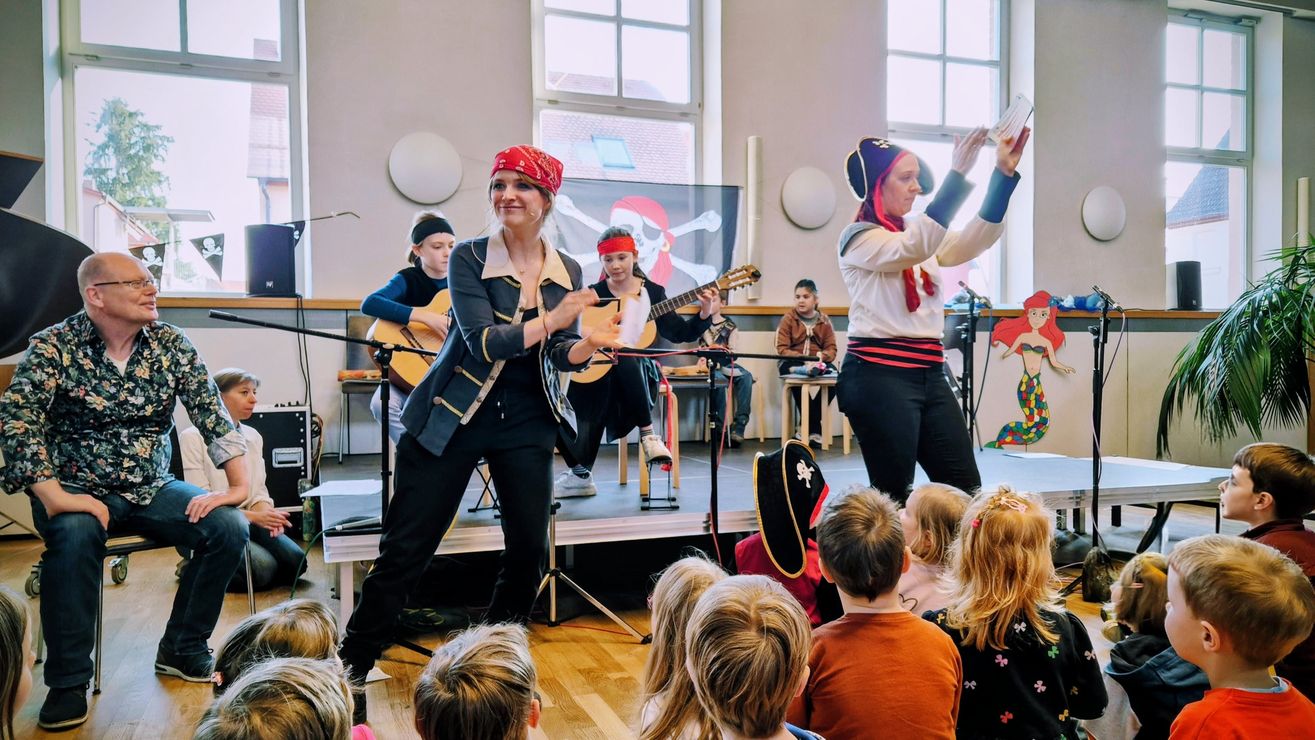 als Piraten verkleidete Lehrkräfte mit Musikschüler:innen beim Mitmachkonzert