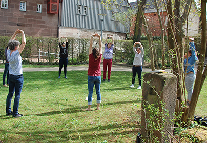 Frauen, die am Ladies Day im Apothekersgarten Dehnübungen machen.