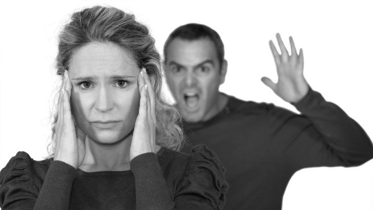 Eine Frau wird vom Partner angeschrieben. Sie hält sich die Ohren zu.