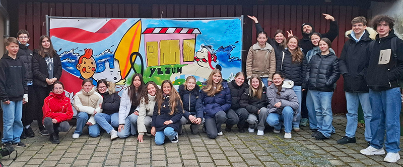 Eine Gruppe deutscher und französischer Jungendlicher vor einem Banner, dass alle gemeinsam gesprayt haben.