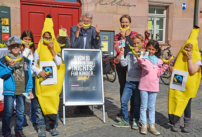 Kinder verteilen zu sammen mit der Lehrerin und Bürgermeister Roland Oeser vor dem Rathaus Faire Bananen.