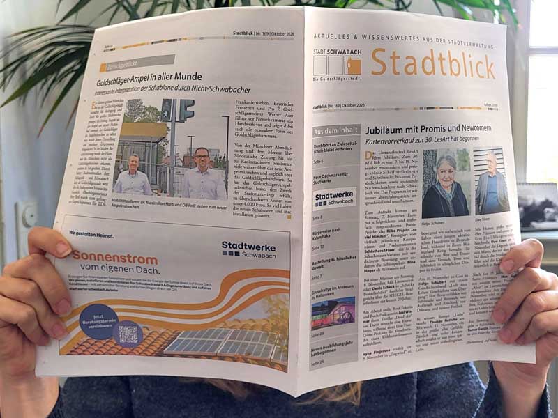 Eine Stadtblick-Ausgabe wird von zwei Händen hochgehalten, als würde die Person dahinter diese lesen