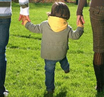 Kind an der Hand der Eltern von hinten Kind an der Hand der Eltern von hinten