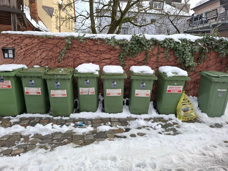 Mehrere Papiertonnen mit schneebedecktem Deckel und der Aufschrift Papier