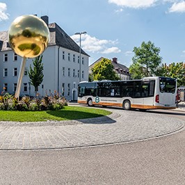 Bild eines Bus, im Vordergrund die Goldkugel im Kreisverkehr am Stadtmuseum